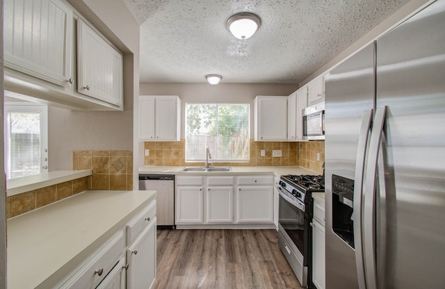 kitchen with appliances with stainless steel finishes, decorative backsplash, white cabinetry, and sink