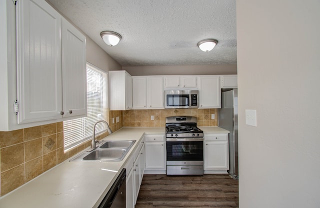 kitchen with appliances with stainless steel finishes, white cabinets, sink, and dark hardwood / wood-style floors