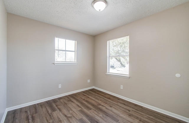 spare room featuring dark wood-type flooring, a textured ceiling, and plenty of natural light