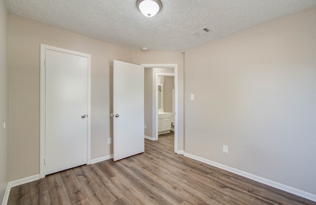 unfurnished bedroom with a textured ceiling and light hardwood / wood-style flooring