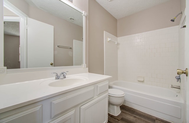 full bathroom featuring toilet, wood-type flooring, vanity, washtub / shower combination, and a textured ceiling