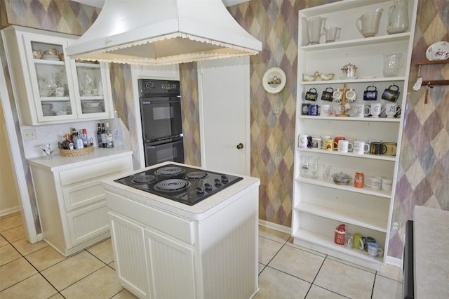 kitchen with black appliances, white cabinets, light tile patterned floors, and premium range hood