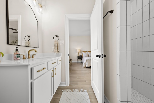 bathroom with a tile shower, vanity, and wood-type flooring