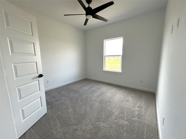 carpeted spare room featuring ceiling fan and baseboards