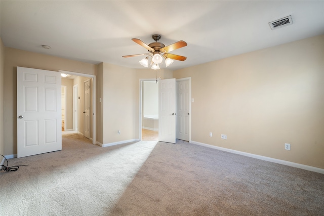 unfurnished bedroom featuring ensuite bathroom, light colored carpet, and ceiling fan