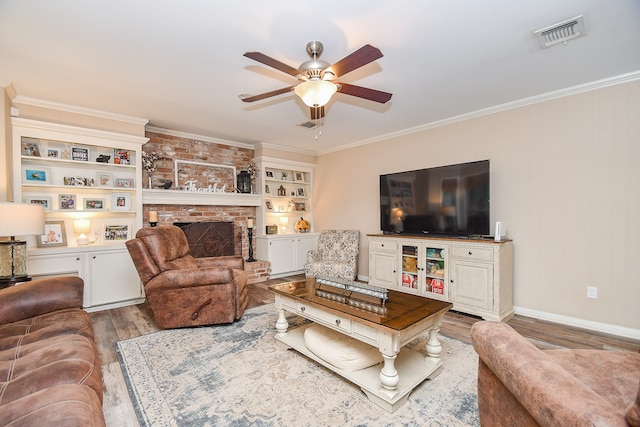 living room with built in shelves, hardwood / wood-style flooring, ceiling fan, and crown molding