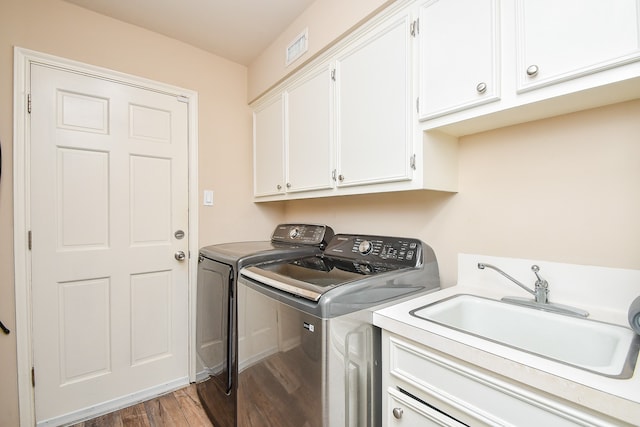 laundry area featuring hardwood / wood-style floors, washing machine and dryer, cabinets, and sink