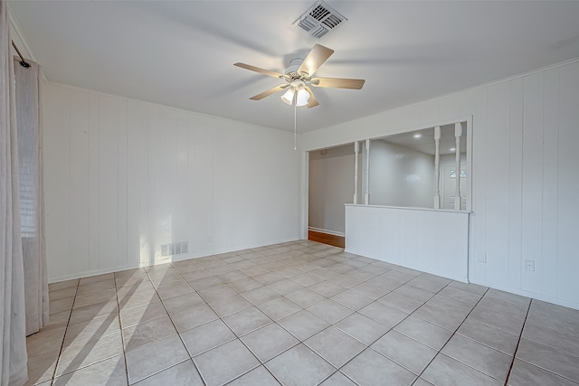 tiled spare room with wood walls and ceiling fan