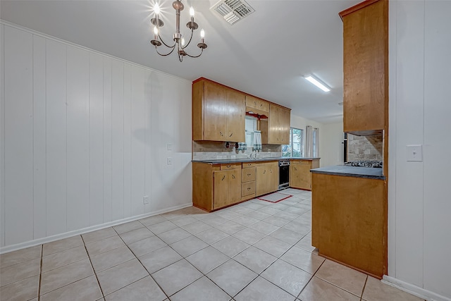 kitchen with tasteful backsplash, sink, stainless steel gas stovetop, light tile patterned floors, and a chandelier