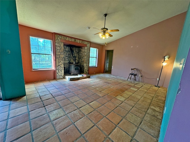 unfurnished living room with a wood stove, a textured ceiling, and ceiling fan