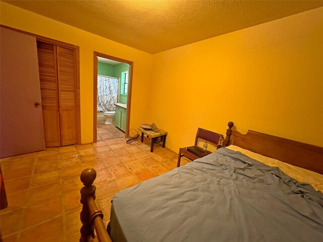 unfurnished bedroom featuring a closet, ensuite bathroom, and a textured ceiling