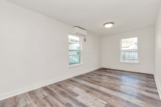 spare room featuring a wall mounted air conditioner and light wood-type flooring