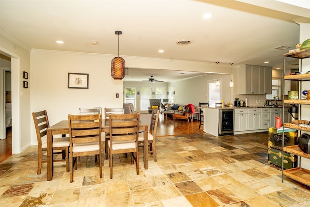 dining space featuring ceiling fan, ornamental molding, sink, and beverage cooler