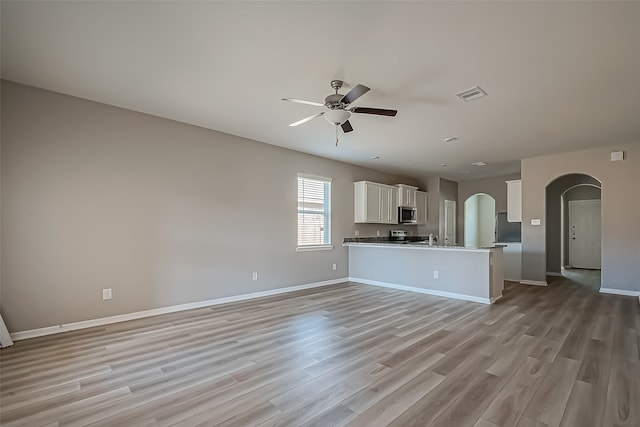 unfurnished living room with sink, light hardwood / wood-style floors, and ceiling fan