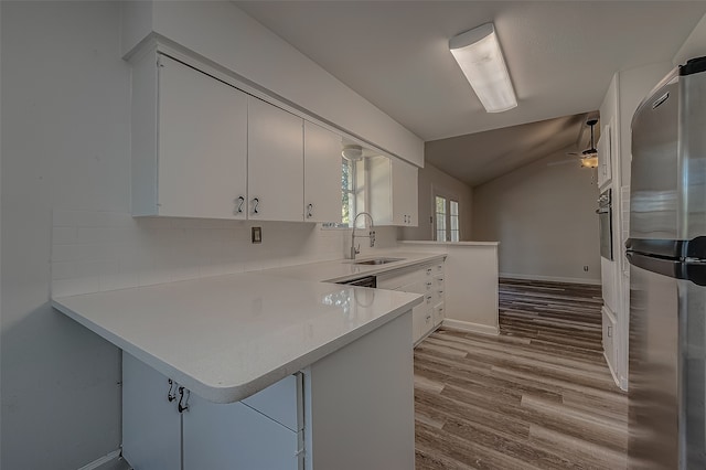 kitchen featuring white cabinets, sink, vaulted ceiling, appliances with stainless steel finishes, and kitchen peninsula