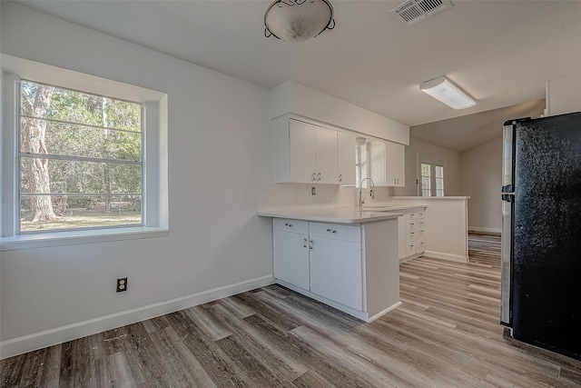 kitchen featuring sink, light hardwood / wood-style flooring, white cabinetry, kitchen peninsula, and stainless steel refrigerator