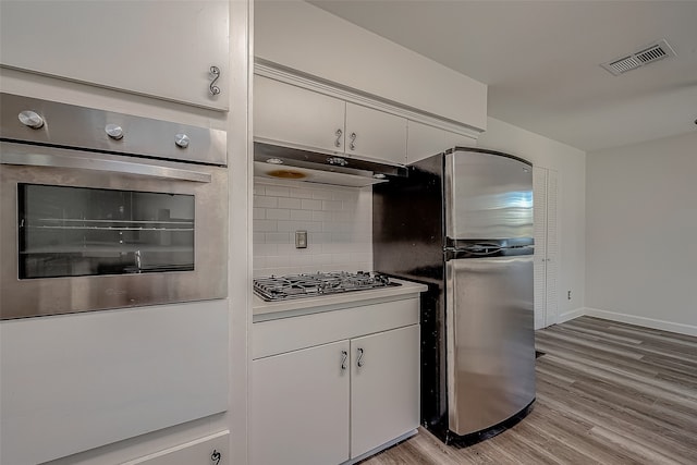 kitchen featuring decorative backsplash, stainless steel appliances, white cabinetry, and light hardwood / wood-style floors