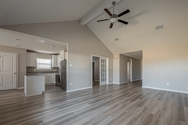 unfurnished living room with light hardwood / wood-style floors, beam ceiling, high vaulted ceiling, and ceiling fan