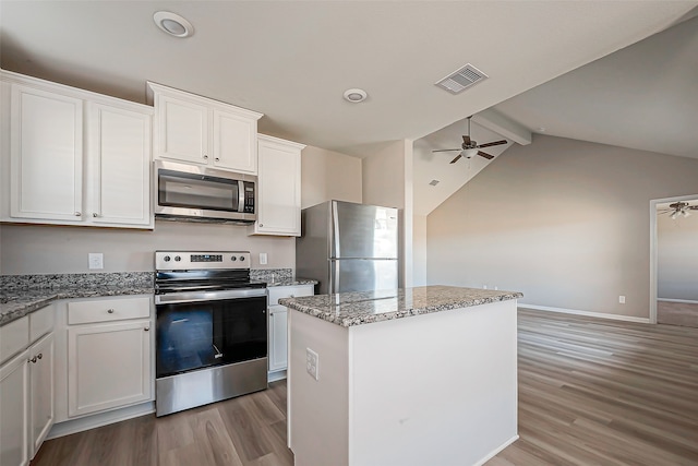 kitchen with a kitchen island, vaulted ceiling with beams, stainless steel appliances, light wood-type flooring, and white cabinetry