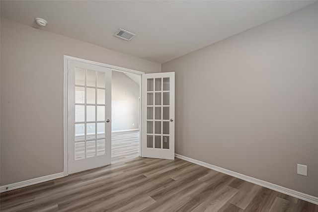 empty room with french doors and hardwood / wood-style flooring