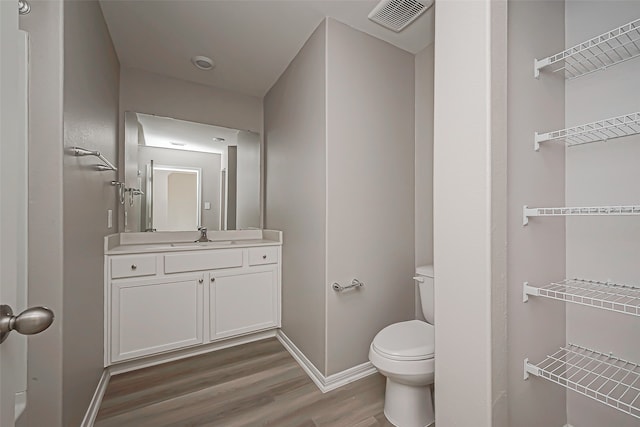 bathroom featuring toilet, hardwood / wood-style flooring, and vanity