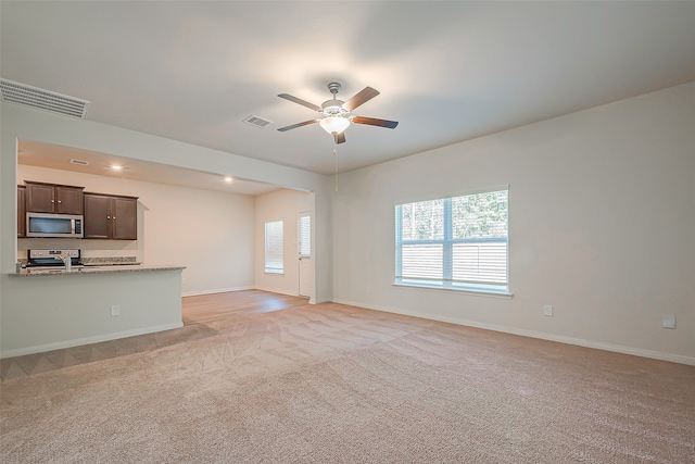 unfurnished living room featuring ceiling fan and light colored carpet