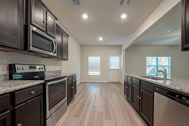 kitchen featuring light hardwood / wood-style flooring, sink, dark brown cabinetry, appliances with stainless steel finishes, and light stone counters