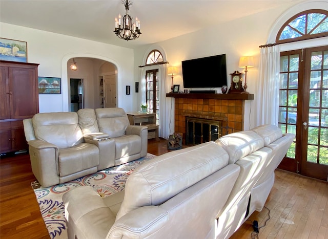 living room with a chandelier, a brick fireplace, and wood-type flooring