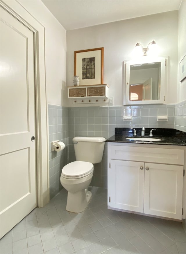 bathroom featuring toilet, vanity, tile walls, and tile patterned flooring