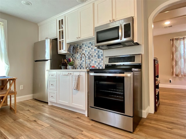 kitchen with light hardwood / wood-style floors, white cabinets, and stainless steel appliances