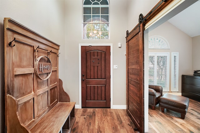 entrance foyer with high vaulted ceiling, a barn door, and hardwood / wood-style floors