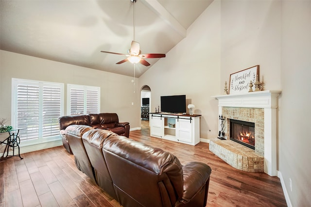 living room featuring hardwood / wood-style flooring, high vaulted ceiling, ceiling fan, and a brick fireplace