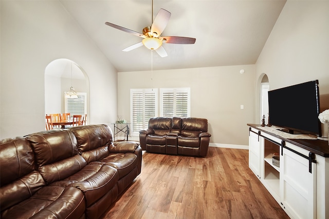 living room with high vaulted ceiling, light wood-type flooring, and ceiling fan with notable chandelier