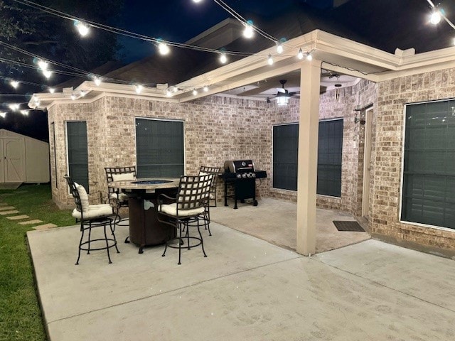 patio at night featuring area for grilling and a shed