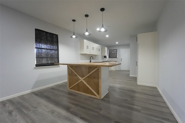 kitchen featuring dark wood-type flooring, white cabinetry, hanging light fixtures, and sink