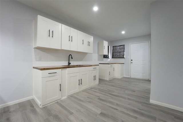 kitchen featuring white cabinetry, sink, and butcher block countertops