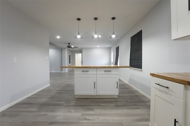 kitchen with white cabinetry, butcher block countertops, light hardwood / wood-style floors, and pendant lighting