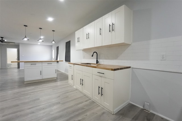 kitchen featuring wooden counters, sink, and white cabinets