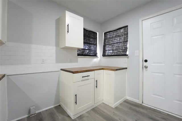 kitchen with white cabinets, light hardwood / wood-style floors, backsplash, and wood counters