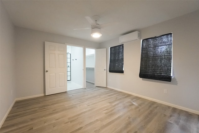 empty room with a wall unit AC, ceiling fan, and light hardwood / wood-style floors