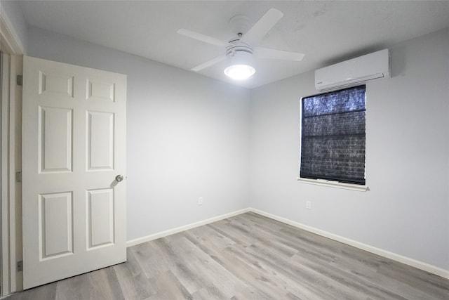 empty room featuring light wood-type flooring, ceiling fan, and a wall mounted air conditioner