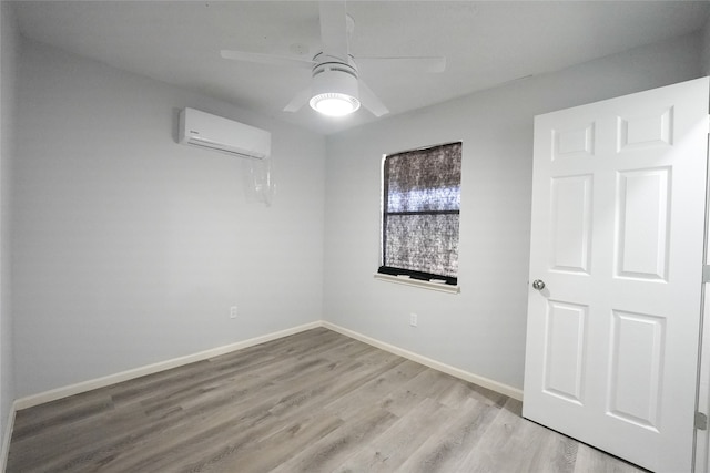 empty room featuring light wood-type flooring, ceiling fan, and an AC wall unit