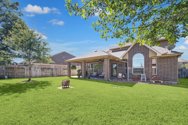 rear view of property with a lawn and an outdoor fire pit