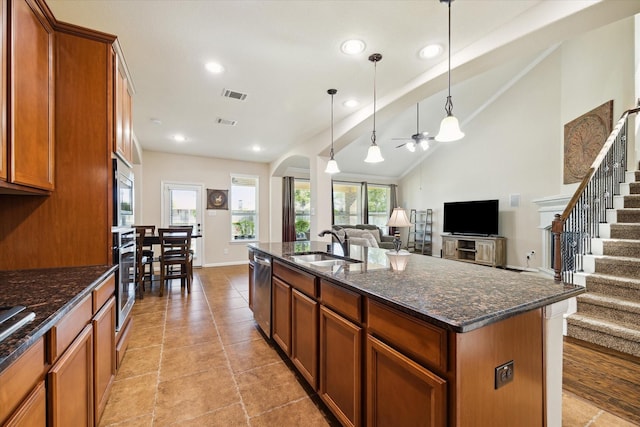 kitchen with sink, decorative light fixtures, vaulted ceiling, dark stone countertops, and a kitchen island with sink