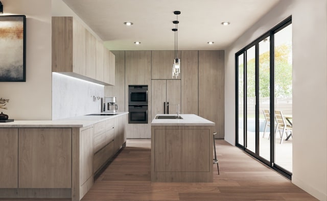 kitchen with a kitchen island with sink, light hardwood / wood-style flooring, light brown cabinetry, paneled fridge, and decorative light fixtures