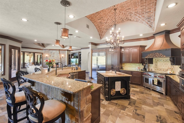 kitchen with high quality appliances, a large island, ornamental molding, sink, and pendant lighting