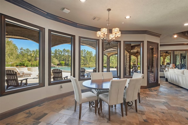 dining room featuring crown molding, a textured ceiling, a water view, and an inviting chandelier