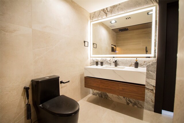 bathroom featuring toilet, vanity, and tile walls