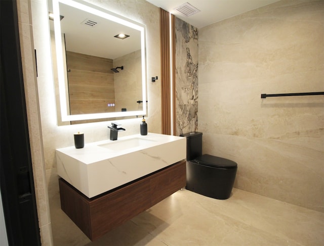 bathroom with tile walls, vanity, tiled shower, and toilet