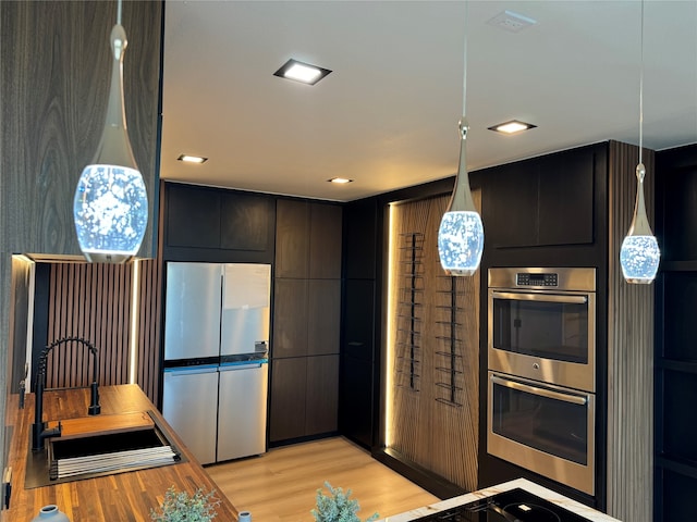 kitchen with sink, appliances with stainless steel finishes, pendant lighting, and light wood-type flooring